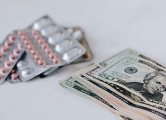 Jak wielkie koncerny kształtują ceny leków i suplementów Co może zrobić zwykły pacjent Plik dolarów obok blistrów drogich leków na białym stole